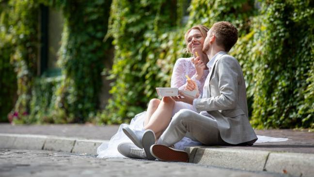 lustiges Brautpaar sitzt auf dem Bordstein